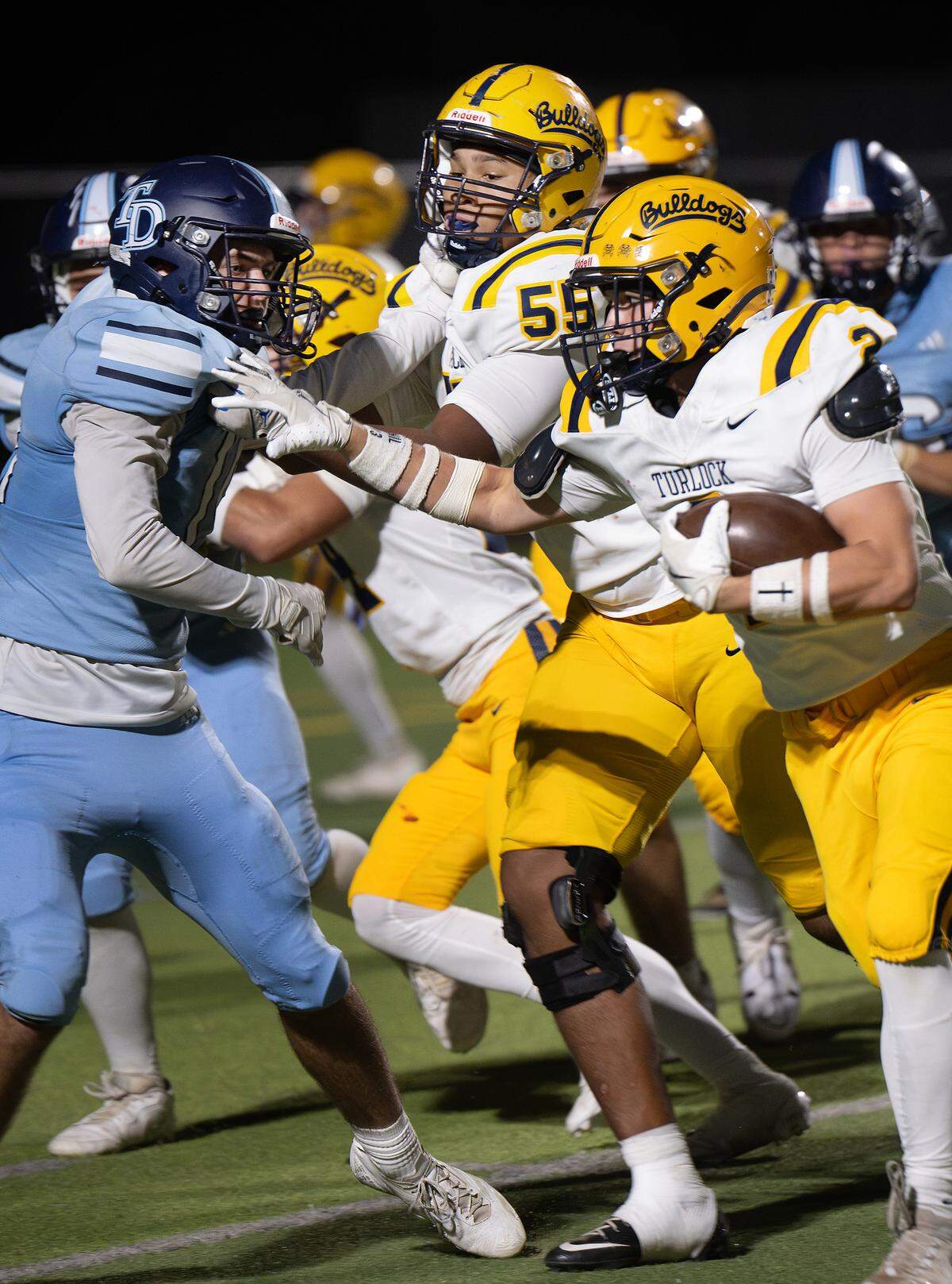 Turlock’s Avery Michael (55) blocks for teammate Kaleb Guinn (2) during the Central California Athletic League game with Downey at Downey High School in Modesto, Friday, Oct. 24, 2025. 