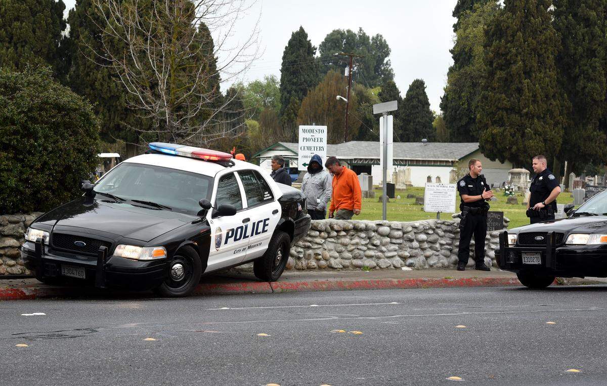 Modesto police officers wait for a tow truck to arrive to remove a patrol car from a cemetery stone wall on Scenic drive near Bodem street in March 2015.