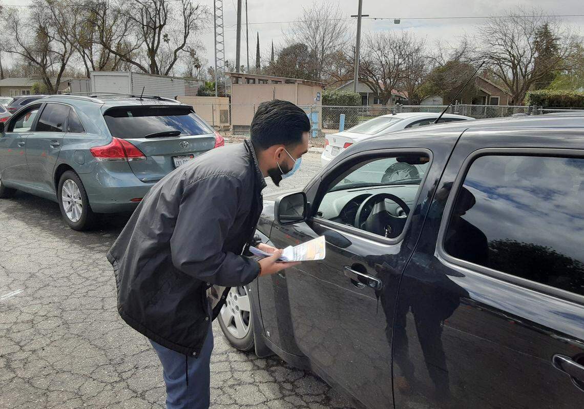 Mobile Outreach Assistance team member Nico Solorio speaks with a driver about the rental assistance program Monday, March 15, 2021, at The Gathering Covenant Church in Patterson, Calif. People were lined up for a food pantry giveaway.