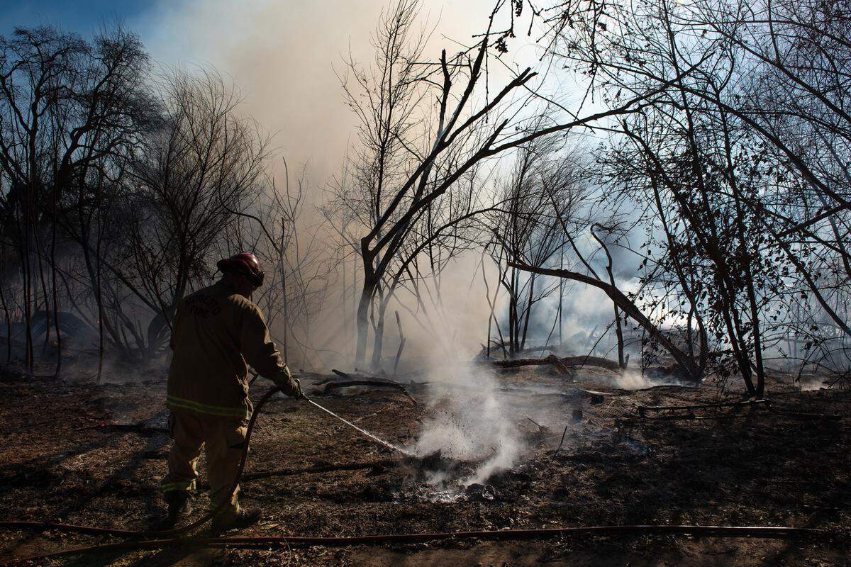A Modesto Firefighter puts out hot spots after a grass fire in the Tuolumne River Regional Park in Modesto, Calif., on Friday, Jan. 20, 2021.