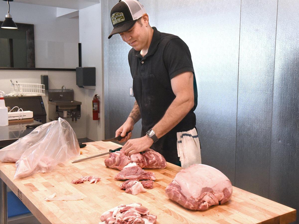 Head butcher Nick McWells cuts up pork shoulder on Thursday May 30, 2019 at The Village Butcher in McHenry Village in Modesto, Calif.