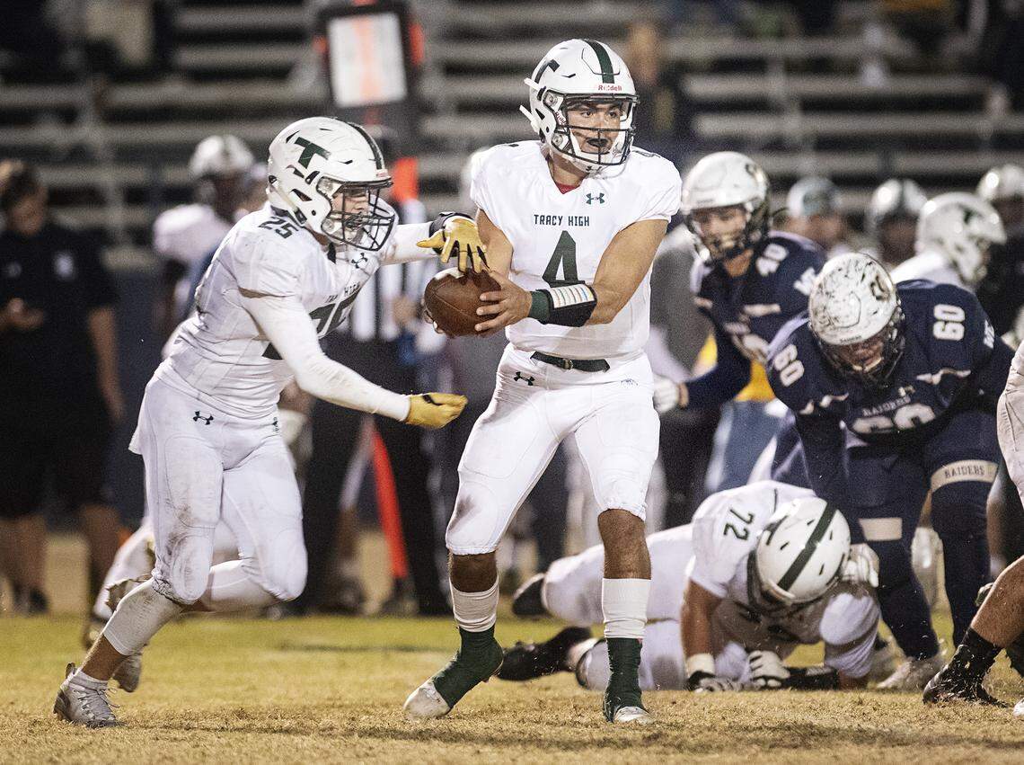 Tracy quarterback Logan Fife hands the ball off to Chase Henderson during the the first round CIF Sac-Joaquin Section Division II playoff game at Central Catholic High School in Modesto, Friday, Nov. 8, 2019. Fife is committed to Fresno State.
