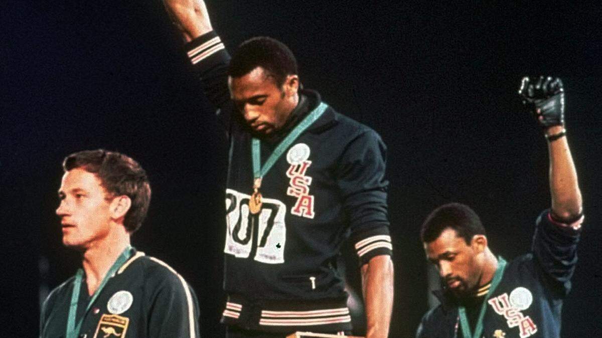 In this Oct. 16, 1968, file photo, U.S. athletes Tommie Smith, center, and John Carlos stare downward while extending gloved hands skyward during the playing of the “Star Spangled Banner” after Smith received the gold and Carlos the bronze for the 200 meter run at the Summer Olympic Games in Mexico City.
