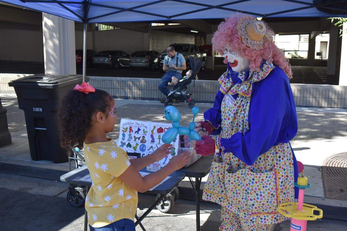 Freckles the Clown makes balloon animals at the Modesto Children’s Museum’s Launch the Adventure street festival on 11th Street downtown Saturday, Aug. 13, 2022.