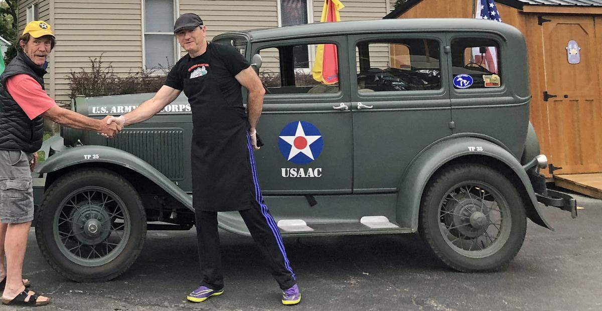 Jay Burbank, at left, and Tully Garrett of Wilmington, Illinois, pose in 2019 after Garrett signed his father’s name on Burbank’s 1931 Model A, in honor of the man’s military service, wartime injuries and experiences. It was the first of hundreds of veterans’ autographs Burbank has collected on the antique auto since then.