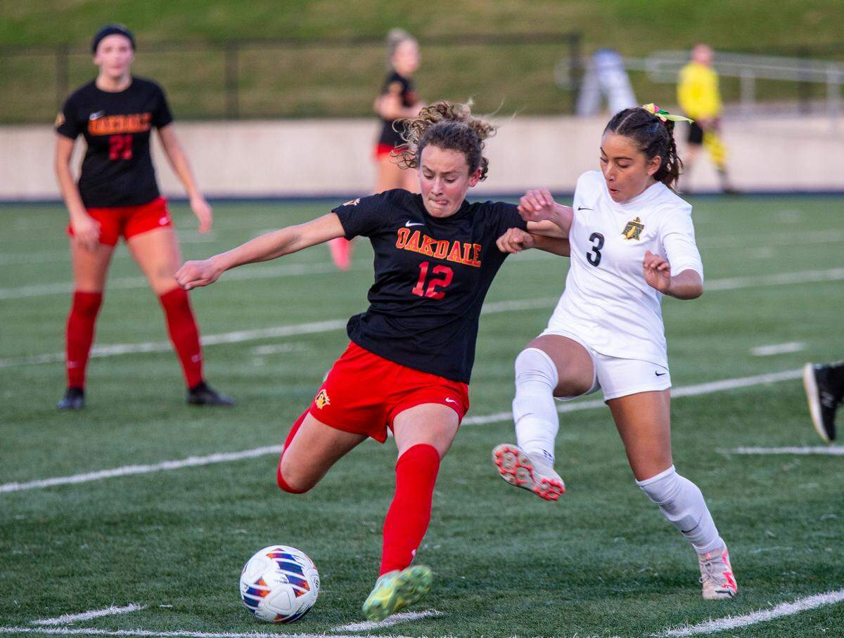 Oakdale High’s Dakota Burford, 12, fights for control of the ball against Hannah Hopkins, 3, of Rio Americano High during the Sac-Joaquin Section Division III Section Championship match Thursday Feb. 22, 2024 at Cosumnes River College.