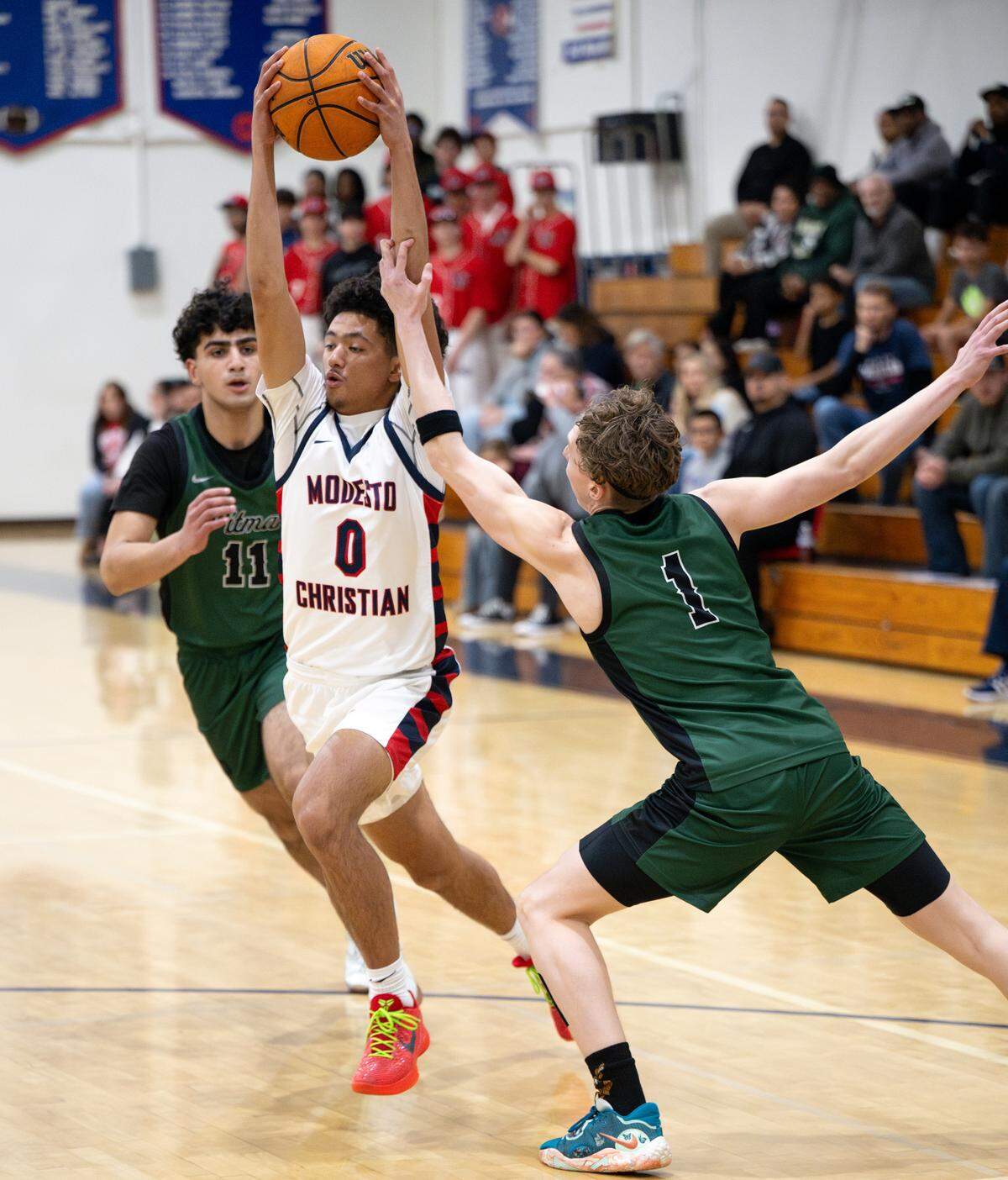 Modesto Christian’s Myles Jones drives past Pitman’s Avery Sanchez (1) and Abhiraj Cheema left, during the Sac-Joaquin Section Division I playoff game at Modesto Christian High School in Salida on Wednesday, Feb. 19, 2025.