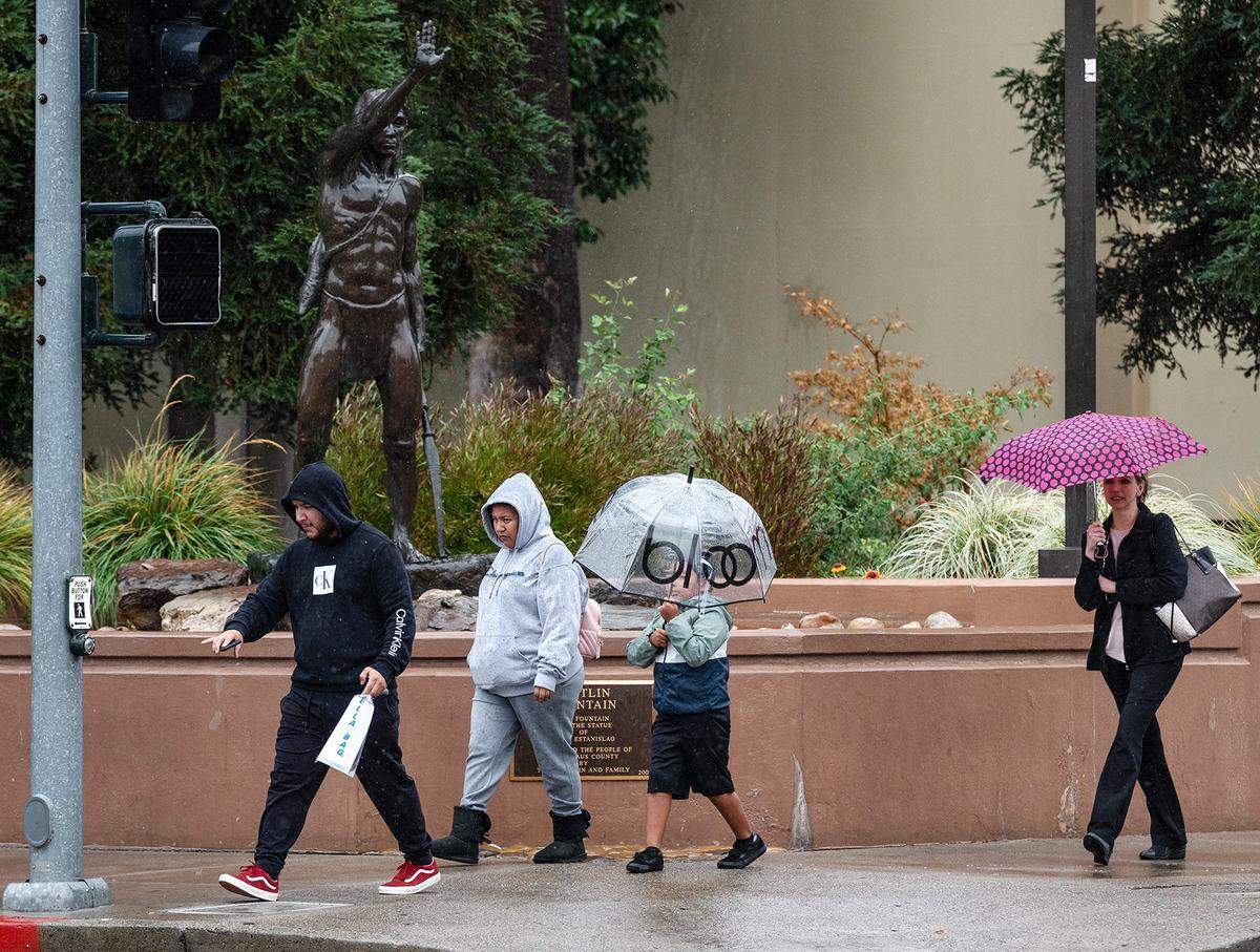 People break out the umbrellas during an afternoon rain storm in Modesto, Calif., Tuesday, Nov. 1, 2022. 