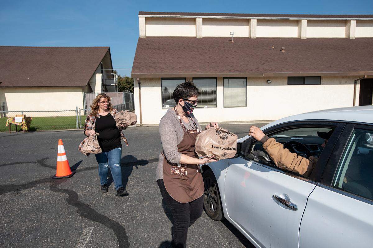 Shawn Butler, right, and Heaven Jobe, left, deliver turkey dinners as Waterford Ministerial Association hosted its seventh annual Community Thanksgiving Dinner in Waterford, Calif., on Thursday, Nov. 25, 2021. Meals were picked up in cars only due to COVID-19 precautions.