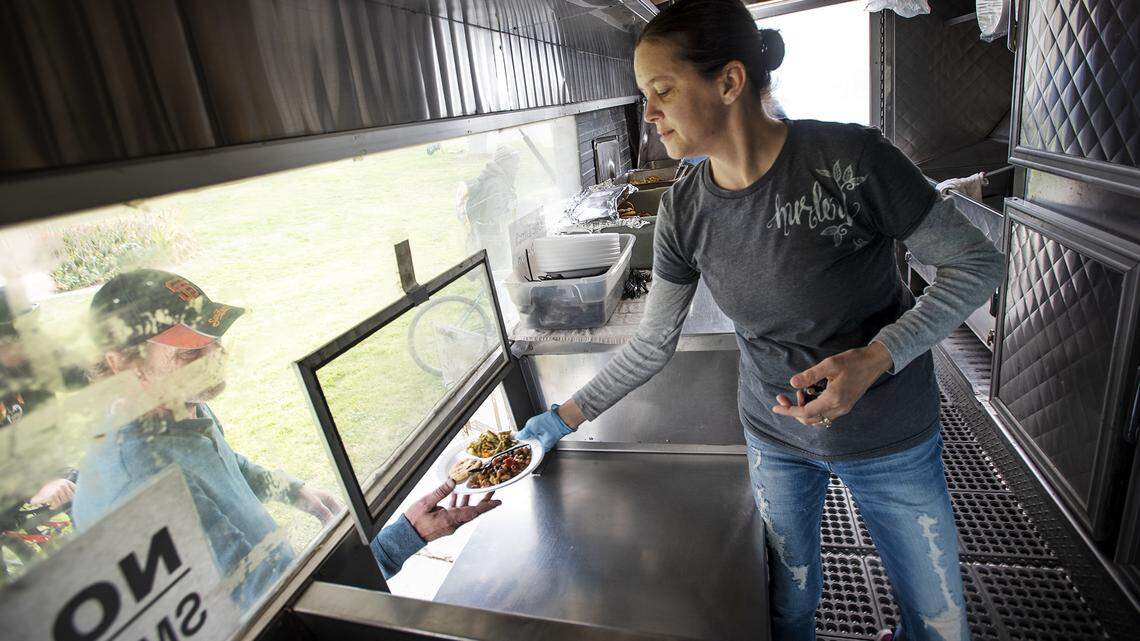 Misty Hough serves lunch with the United Samaritans at Cesar Chavez Park in Modesto, Calif., on Thursday, March 19, 2020. United Samaritans is short on volunteers and are feeling the strain of serving homeless people and the poor due to the effect of the coronavirus.