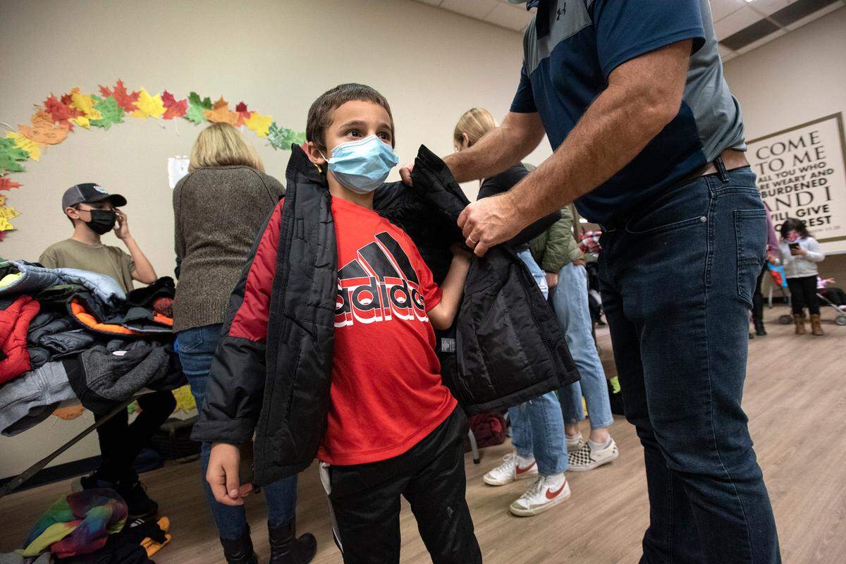 Kaleb Wilson, 8, is fitted with a new jacket during the Great Thanksgiving Banquet & Bundle-Up at the Modesto Gospel Mission in Modesto, Calif., on Wednesday, Nov. 24, 2021.