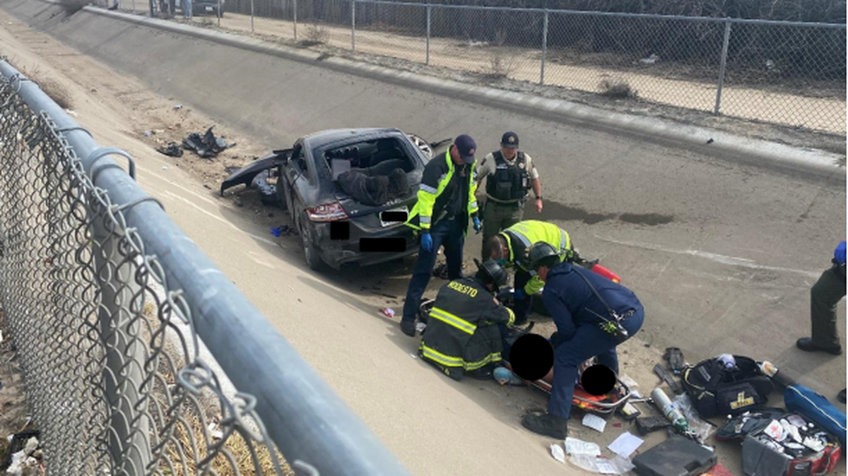 A photo by Modesto Fire, obscuring the victim’s face, shows firefighters providing aid to a man who crashed into a canal following a shooting on Tuesday, March 1, 2022.
