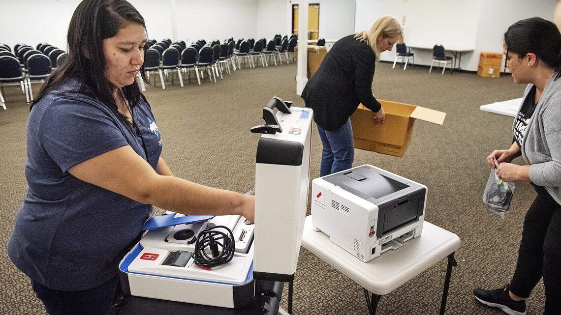 Stanislaus County election office clerk Arianna Paz, left, sets up a “touch writer” voting station at a satellite office at the Salida Library in Salida, Calif., on Friday, Feb. 28, 2020.