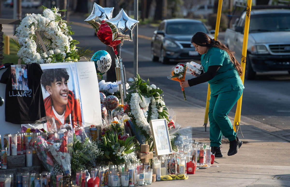Silvana Villarreal places flower and candles on a large memorial at the site of the fatal crash on Carver Road in Modesto, Calif., on Thursday, Feb. 3, 2022. Three Davis High students were killed in the crash.