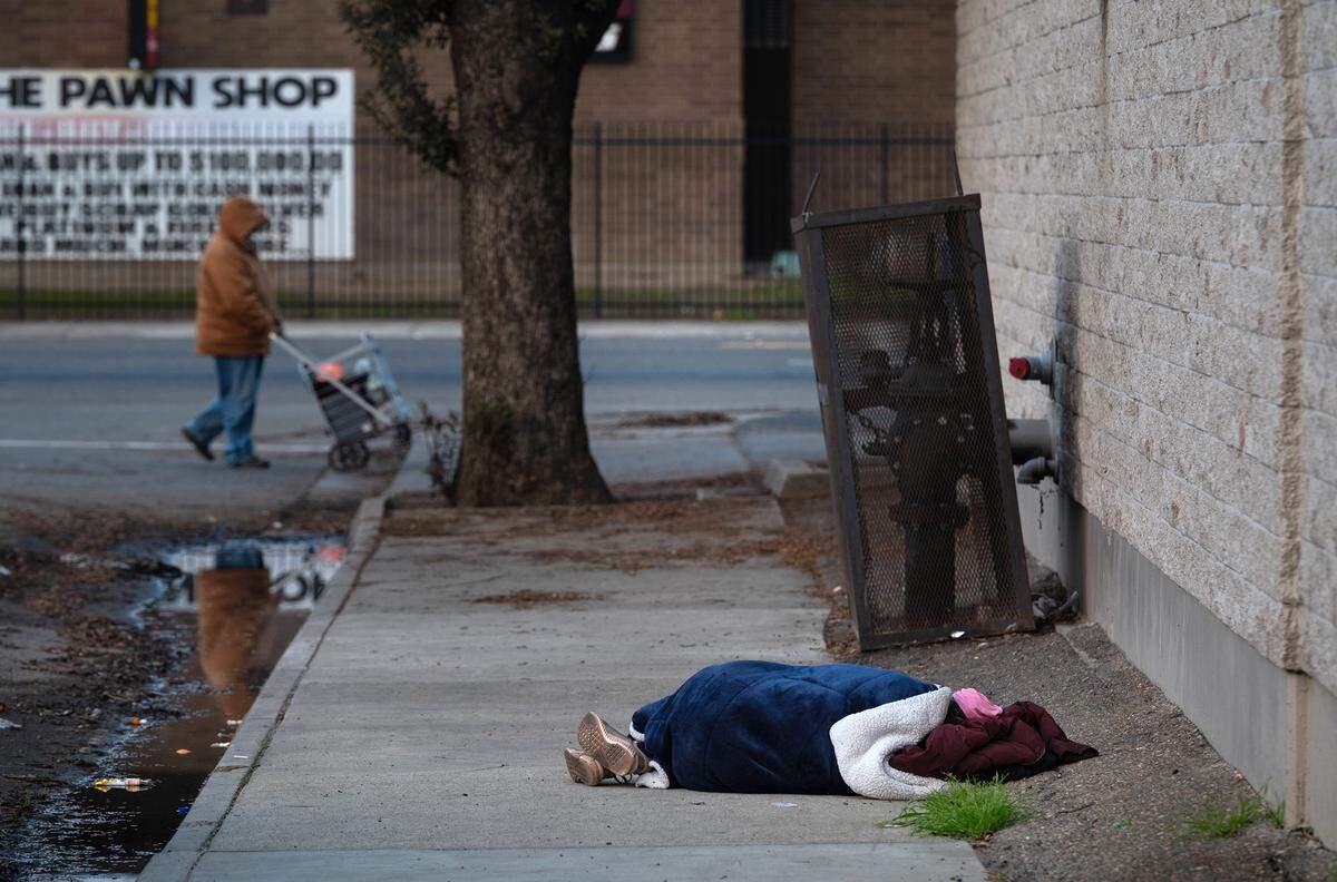 A homeless person sleeps behind the Modesto Gospel Mission on Yosemite Boulevard in Modesto on Jan. 12, 2024.