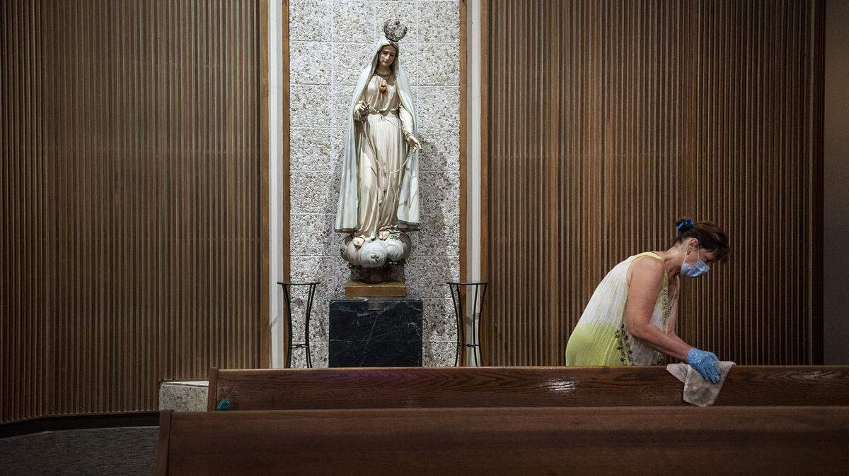 Fatima Medina cleans pews at Sacred Heart Church in Turlock, Calif., on Thursday, May 28, 2020.