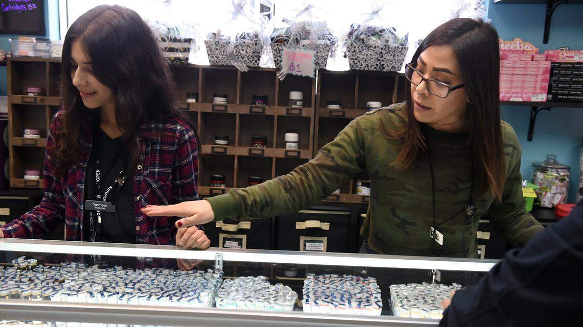 Budtender Amelia Aragon (right) shows a customer pre-roll tubes as Yasmeen Macias looks on at left on Friday afternoon December 7, 2018 at The People’s Remedy marijuana dispensary in Modesto, Calif.