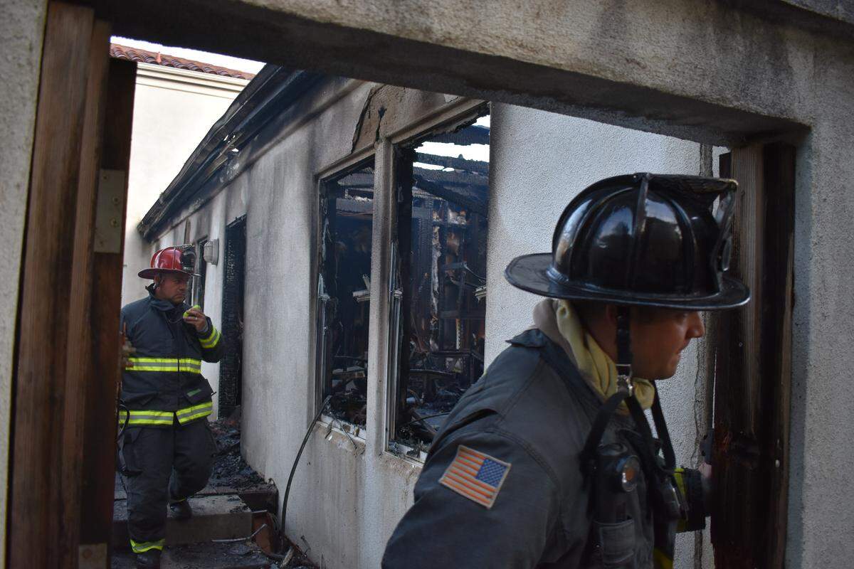 Firefighters were called back to the home of Rick and Judi Dalton on Monday to put out hot spots from a fire Sunday night. Here, they check out the home office, which was gutted by the fire.