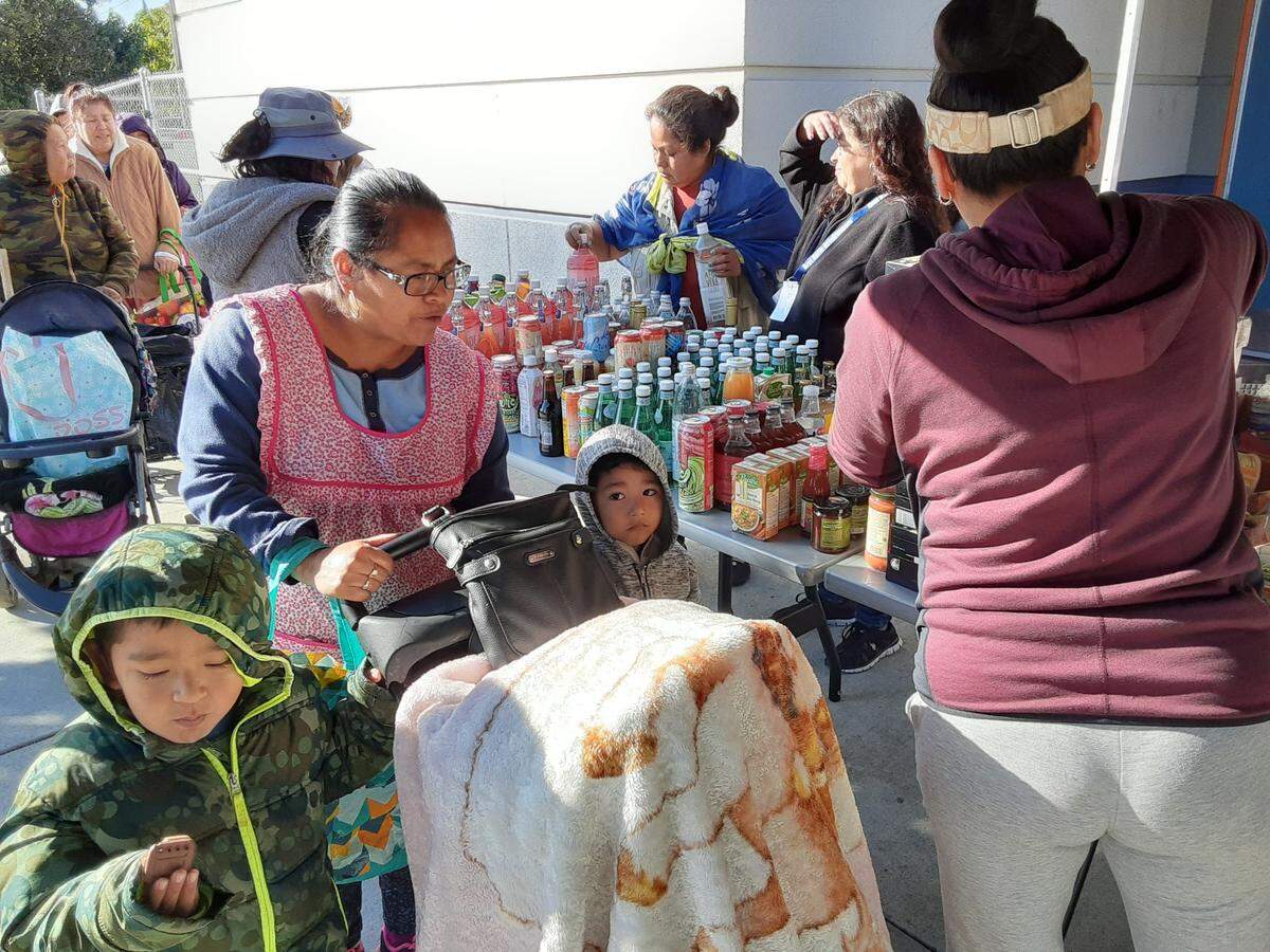 A mom and her children are helped by volunteers at Bret Harte Elementary School in south Modesto on Thursday, Nov. 10, 2022, during the Second Harvest food bank’s Fresh Food 4 Kids program.