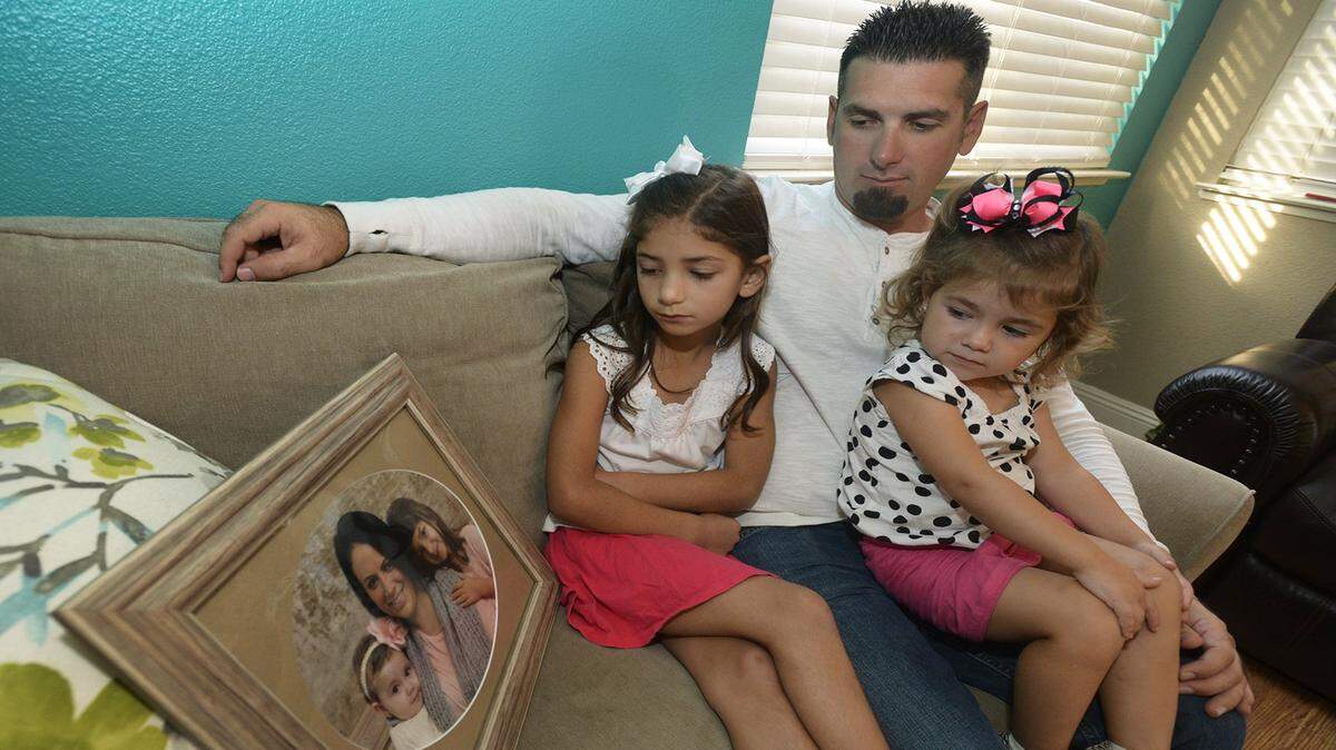 Danika, age 7, her dad Ryan and sister, Aubree, age 2, look at a photo taken of wife and mother Nicole with Aubree and Danika before her death. Dias lost his wife Nicole more than 20 months ago after hospital staff allegedly incorrectly diagnosed her condition.