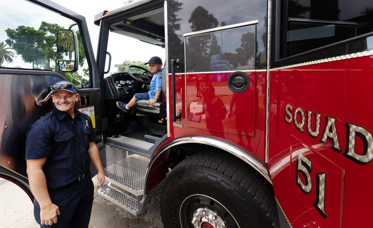 Pablo Jimenez, 3, and Patterson Fire Department firefighter Richard Siler pose for a picture during National Night Out at North Park in Patterson, Calif., Tuesday, Aug. 1, 2023.