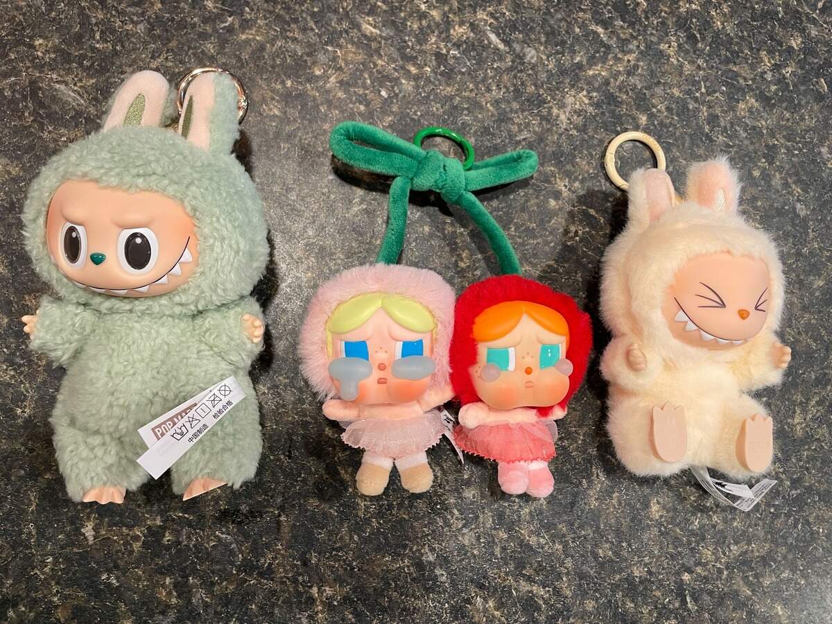 A selection of Pop Mart toys including Green Grape Labubu from The Monsters: Exciting Macaron series, I Love You Cherry Much from Crybaby: Crying for Love series and DaDa Labubu from The Monsters: Have a Seat series
