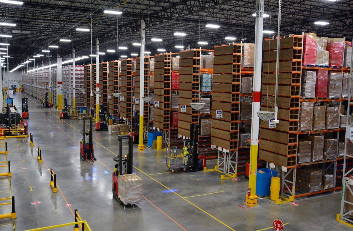 Workers drive power lifts across the floor of the new 1.1-million-square-foot Amazon fulfillment center that has opened in Turlock, Calif. Oct. 20, 2022.