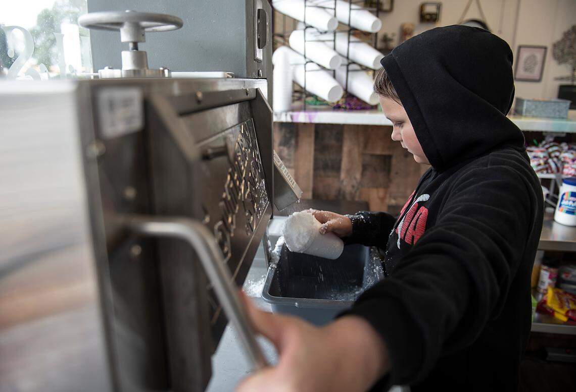 Dylan McDonald demonstrates how to make shaved-ice at his family shave-ice shop in Oakdale, Calif., on Monday, Dec. 27, 2021. He uses the money he makes from tips to buy candy in bulk and sell it for a profit, he said.