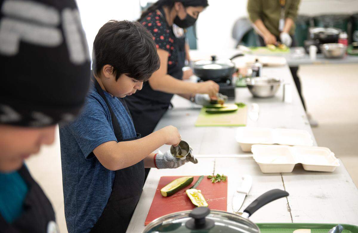 Rey Parra, 10, spoons oil and garlic onto zucchini during Junior Chefs cooking class for children at Robertson Road School in Modesto, Calif., Thursday, April 6, 2023.