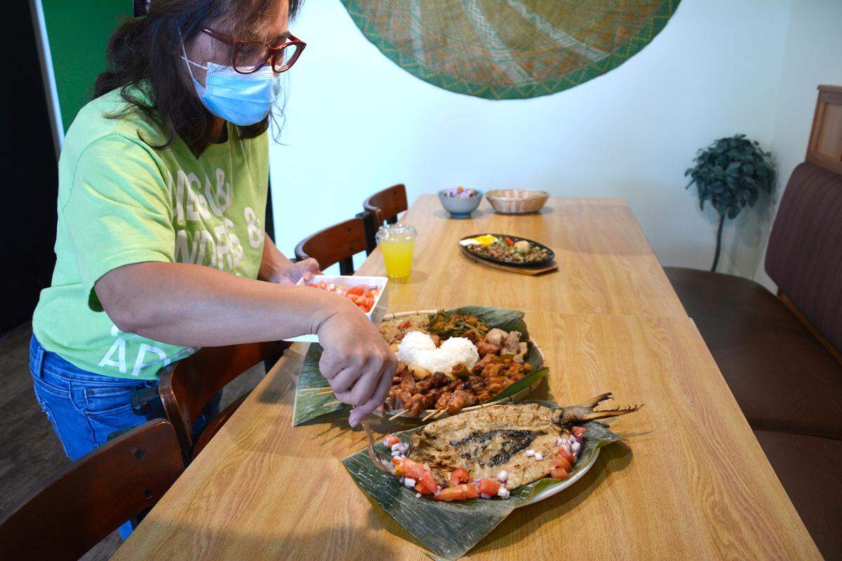 Tatum Hontiveros, owner of the new Filipino restaurant Kusina in Century Center, puts the finishing touches on a dish in Modesto, Calif. May 12, 2021.