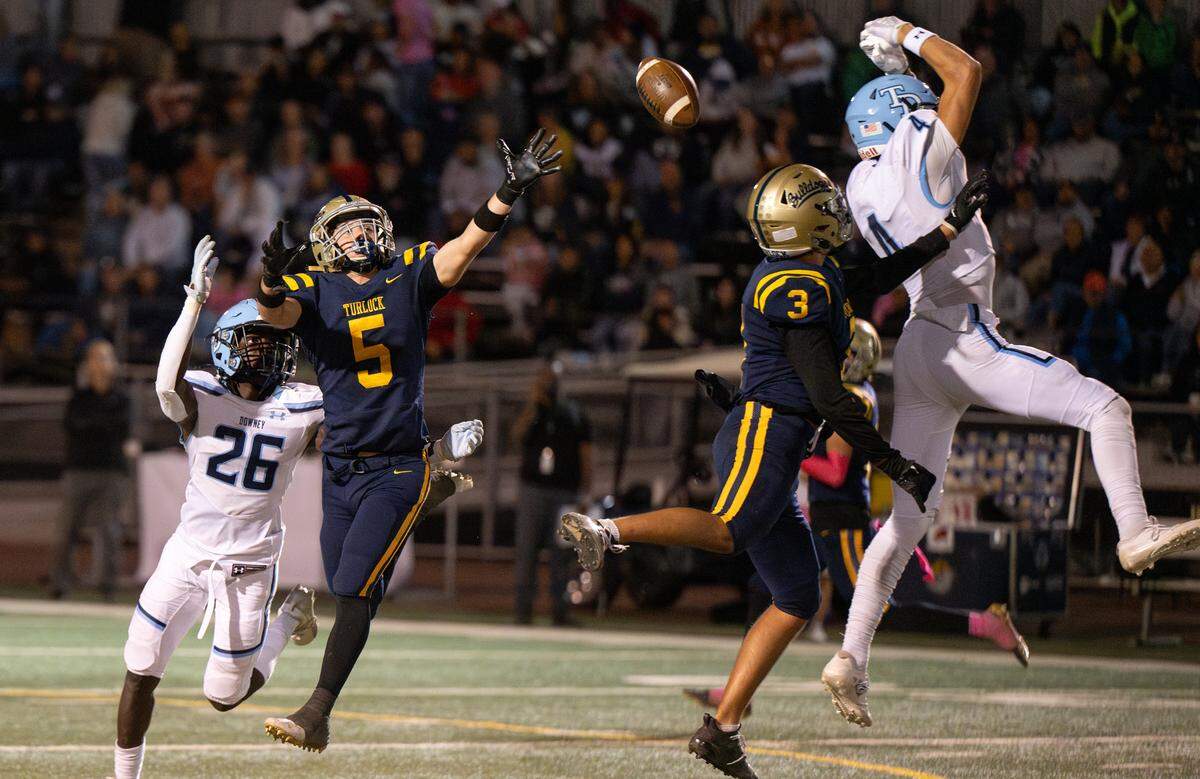 Turlock and Downey players attempt to catch a tipped ball during the Central California Athletic League game at Turlock High School in Turlock, Friday, Oct. 18, 2024.