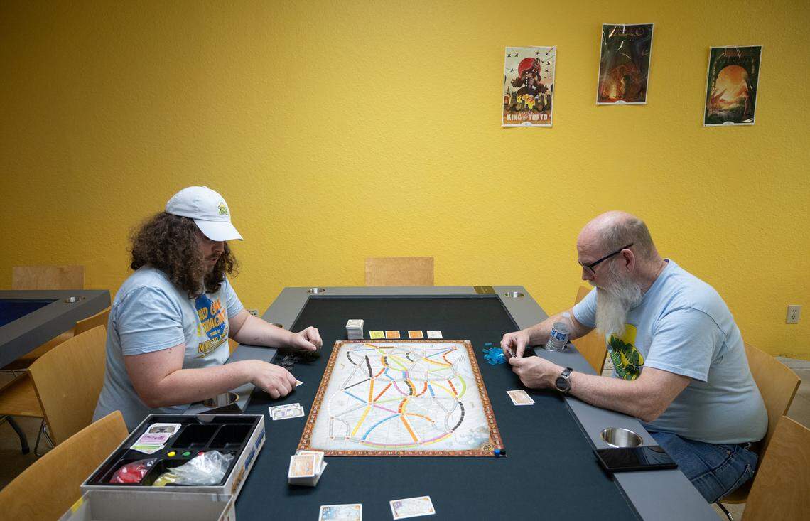 Rob Van Tuinen, left, and his father Bob Van Tuinen demonstrate the game Ticket to Ride on one of the gaming tables at Meeple Valley Board Game Cafe in Modesto, Calif., Thursday, March 21, 2024.