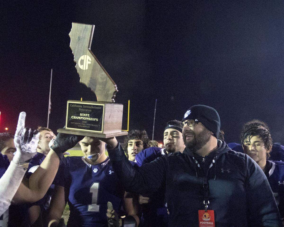 Denair head coach Anthony Arias holds the CIF Trophy after winning the CIF Division 7-AA championship game between Denair and Santee at Denair High School in Denair California on December 1, 2018.