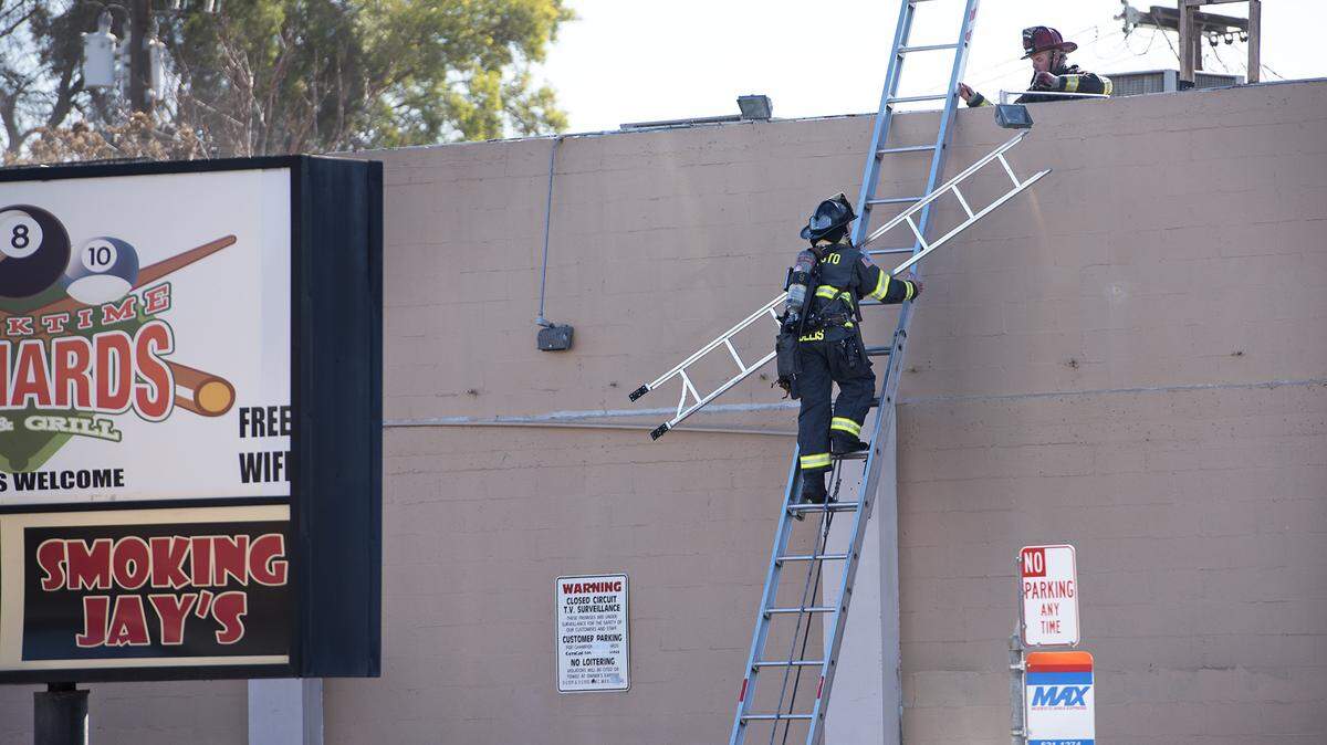 Firefighters climb to the roof of a building at 302 McHenry Ave. after getting called to the scene for reports of smoke.