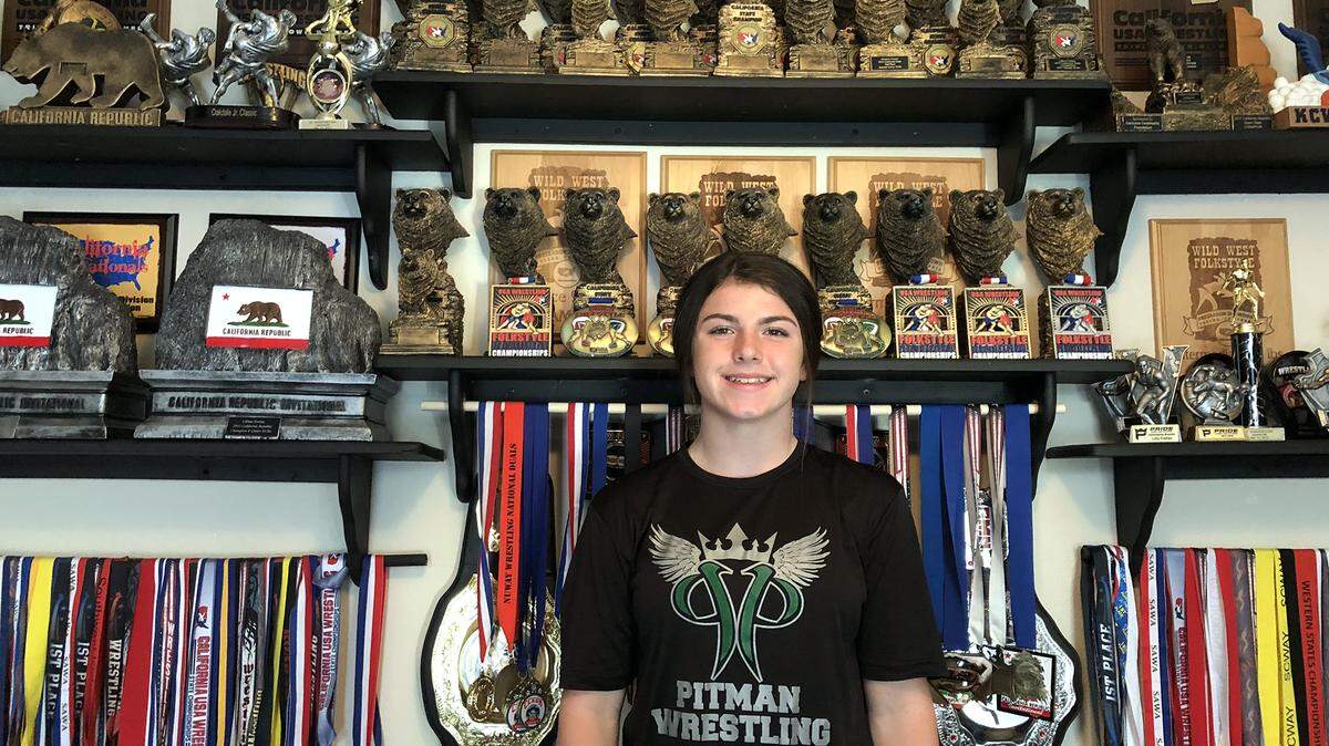 Pitman High freshman wrestler Lilly Freitas pictured at her home standing next to her trophies in the summer of 2018.