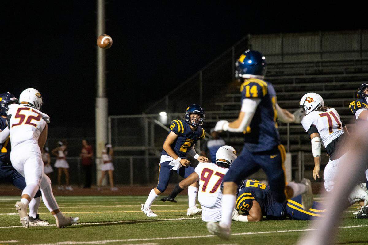 Turlock High quarterback Vincent Gonzales (2) watches his pass to Carter Crivelli (14) fly through the air during the first half of Friday night’s game against Clovis West.