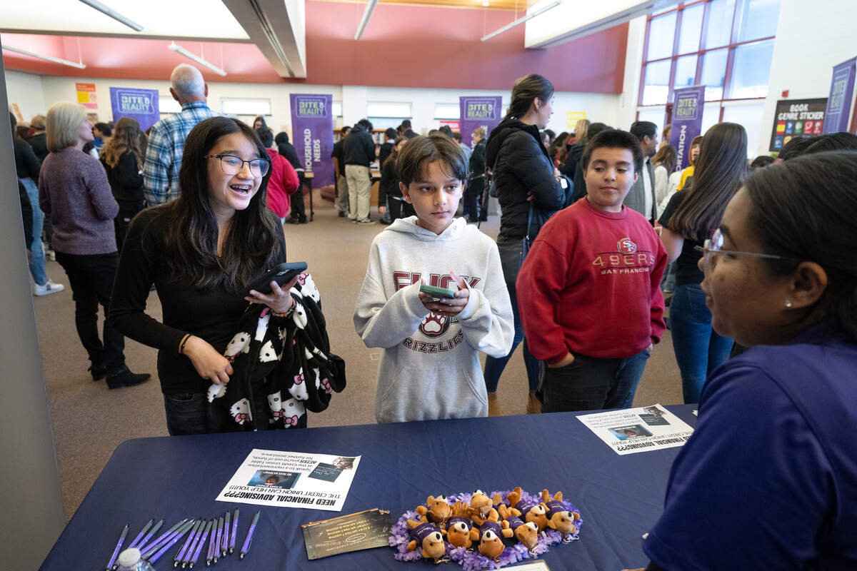 Chantelle Curtis from Valley First Credit Union, right, talks with 7th grade students Hannah Villarreal, left, and Aansh Singh, middle, during an after school financial literacy event at Glick Middle School in Empire, Wednesday, Dec. 11, 2024. Students were given a career and monthly salary and went to different stations to purchase goods as part of a simulation that shows students real world financial realities.