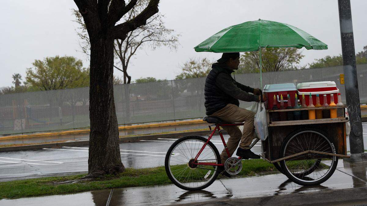 A street vendor rides during a rainstorm in Modesto, Calif., Tuesday, March 28, 2023.