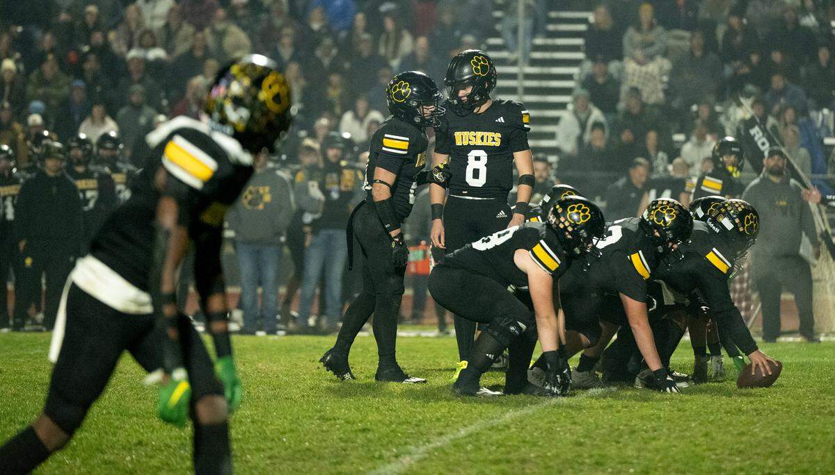 Hughson quarterback Robert McDaniel and Eli Wilbanks huddle before a play during the CIF Northern California Division 4-AA Bowl Game with St. Vincent de Paul in Hughson, Friday, Dec. 6, 2024.