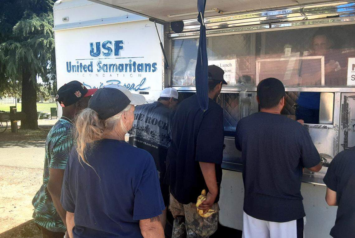 People gather Friday, June 24, 2022, in Modesto’s Dr. Martin Luther King Jr. Park for lunch from one of United Samaritans Foundation’s food trucks.