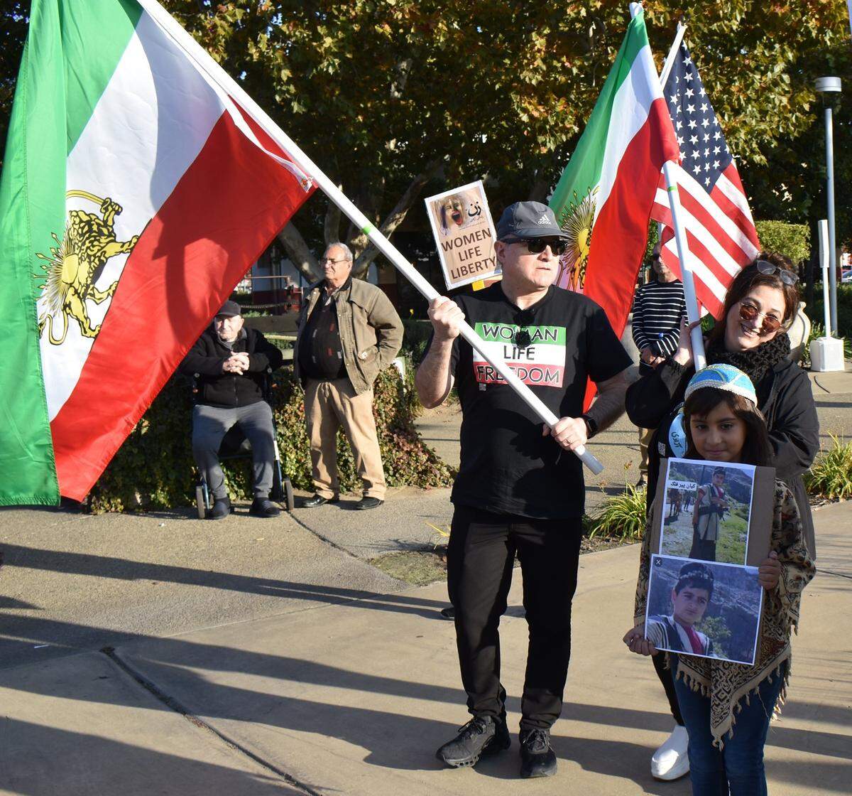 Dozens of people gathered at a Turlock intersection the afternoon of Sunday, Nov. 20, 2022, to protest against the Islamic Republic of Iran. They called for democracy, human rights and an end to the Islamic regime. Standing center and holding the flag of the National Union for Democracy in Iran, is Siamak Namdarian, a Fresno dentist who was among the organizers of the demonstration.