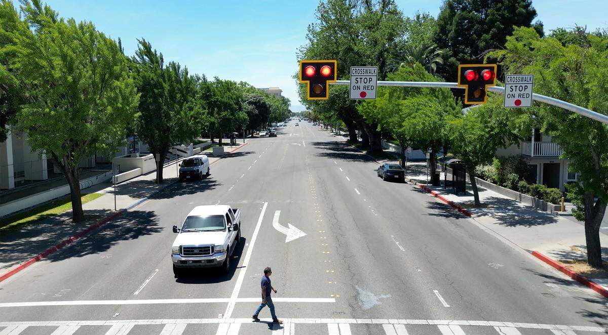 A pedestrian crosses I Street at 16th Street using the new HAWK crosswalk in Modesto, Thursday, May 15, 2025. The light system has been installed to make crossing the 4-lane I street safer for pedestrians. The light sequence starts with a blinking yellow to caution motorists to slow down, followed by a solid yellow light to warn drivers to prepare to stop, then a solid red light for drivers to stop, and finishes with a blinking red that allows drivers to proceed with caution.