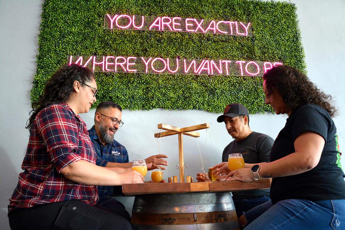 WhichCraft, a new craft brew taproom, has opened in downtown Gustine, California. Co-owners and married couples (L-R) Jackie and Sam De La Cruz and Joe and Lizett Garcia play a table game inside the space.