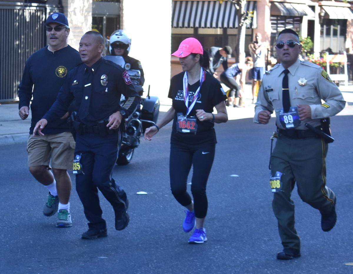 Running in full uniform, Turlock Police Department lieutenant and cancer survivor Joey Mercado, center, nears the finish line of the Peace Officer Memorial Run half marathon in downtown Modesto on Sunday morning, Oct. 6, 2019.