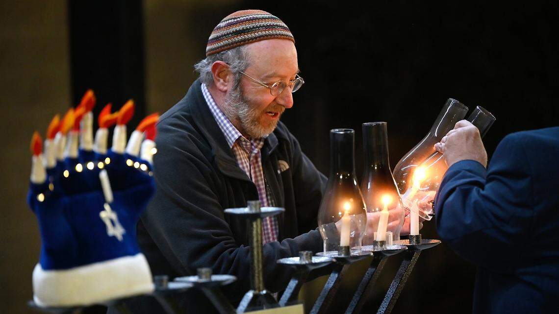 Congregation Beth Shalom Rabbi Shalom Bochner lights candles with the help of Anthony Gonsalves, during the lighting of the menorah on the third day of Hanukkah outside the Gallo Center for the Arts in Modesto, Calif., Tuesday, Dec. 20, 2022.