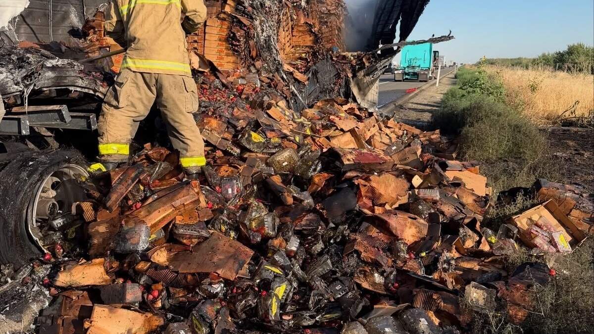 Firefighters extinguish hot spots after a trailer carrying approximately 22,000 pounds of strawberries caught fire Thursday morning along northbound Interstate 5 north of Howard Road near Westley.