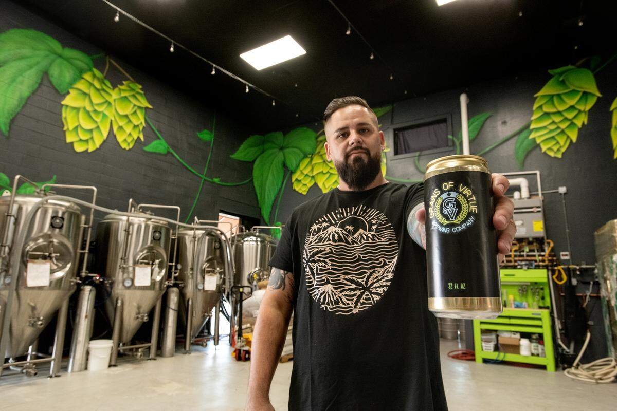 Grains of Virtue Brewing Company co-owner Kris Panelle holds one of their 32 cans of beer in Oakdale, Calif., on Thursday Oct. 23, 2020.