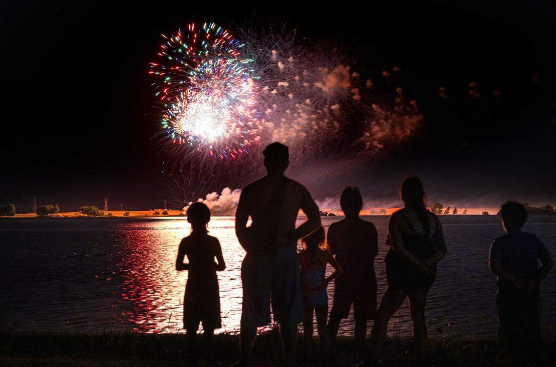 A family watches the Fourth of July fireworks presentation at Woodward Reservoir in Oakdale, Calif., Saturday, July 1, 2023.