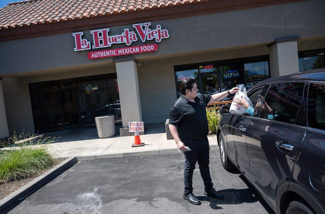 Franky Acosta takes food out to a customer at La Huerta Vieja restaurant in Modesto, Calif., on Friday, May 13, 2022. Acosta says they do want to use food delivery services but offer curbside take-out for their customers.