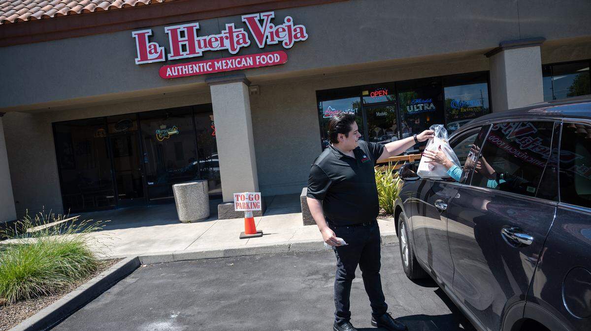 Franky Acosta takes food out to a customer at La Huerta Vieja restaurant in Modesto, Calif., on Friday, May 13, 2022. 